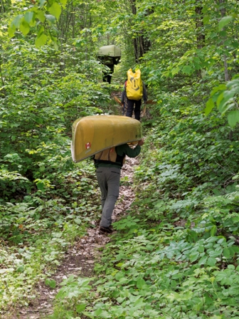 people portaging on a path in forest