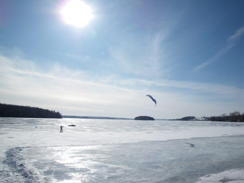 someone flying a kite on a frozen lake