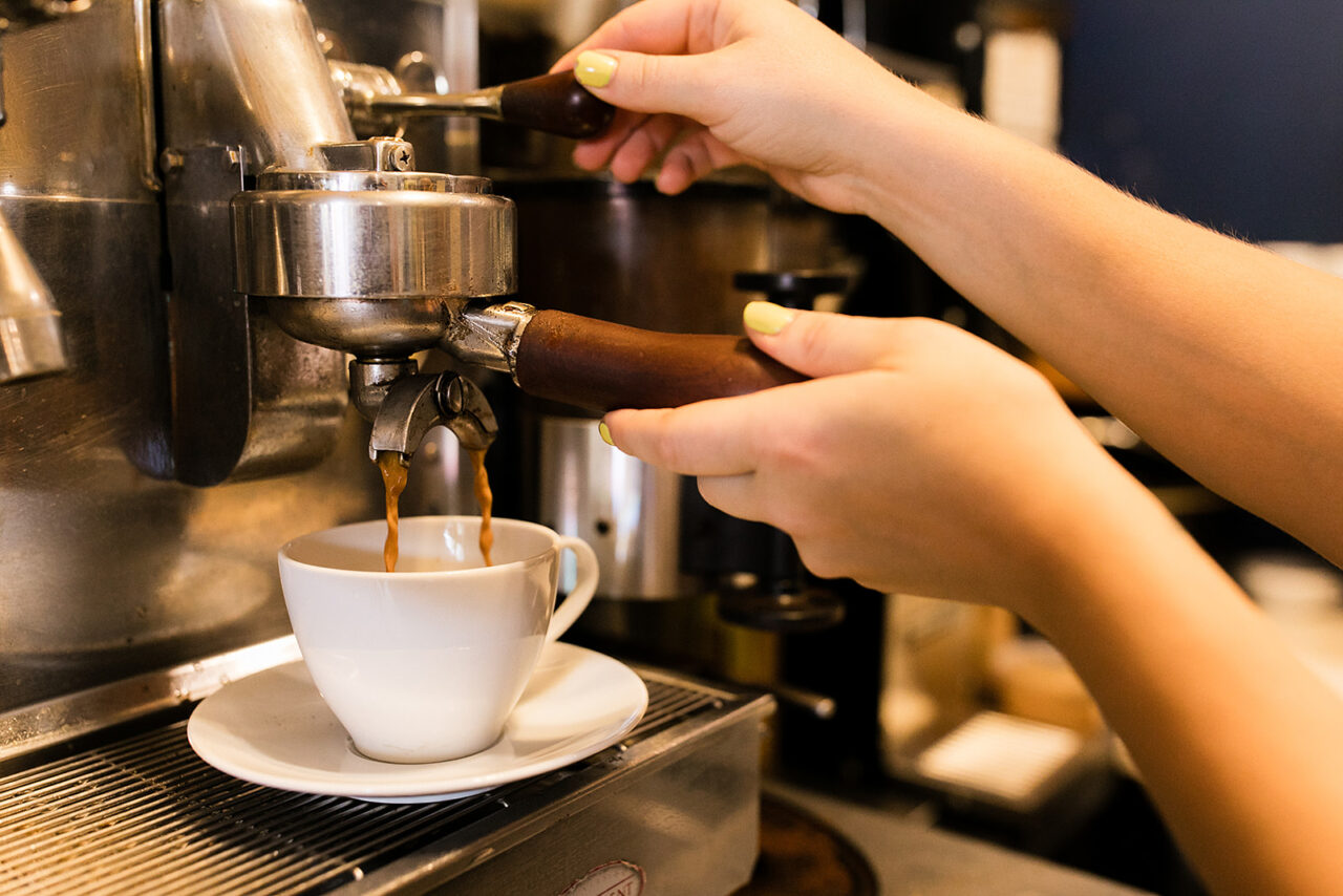 an up-close shot of an espresso machine dispensing a shot of espresso in a ceramic mug