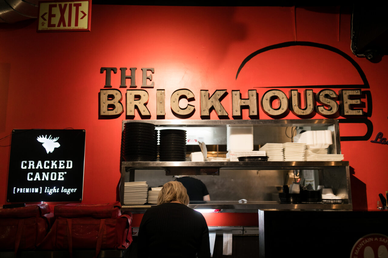 inside a restaurant at the kitchen window with a sign reading 'the brickhouse'