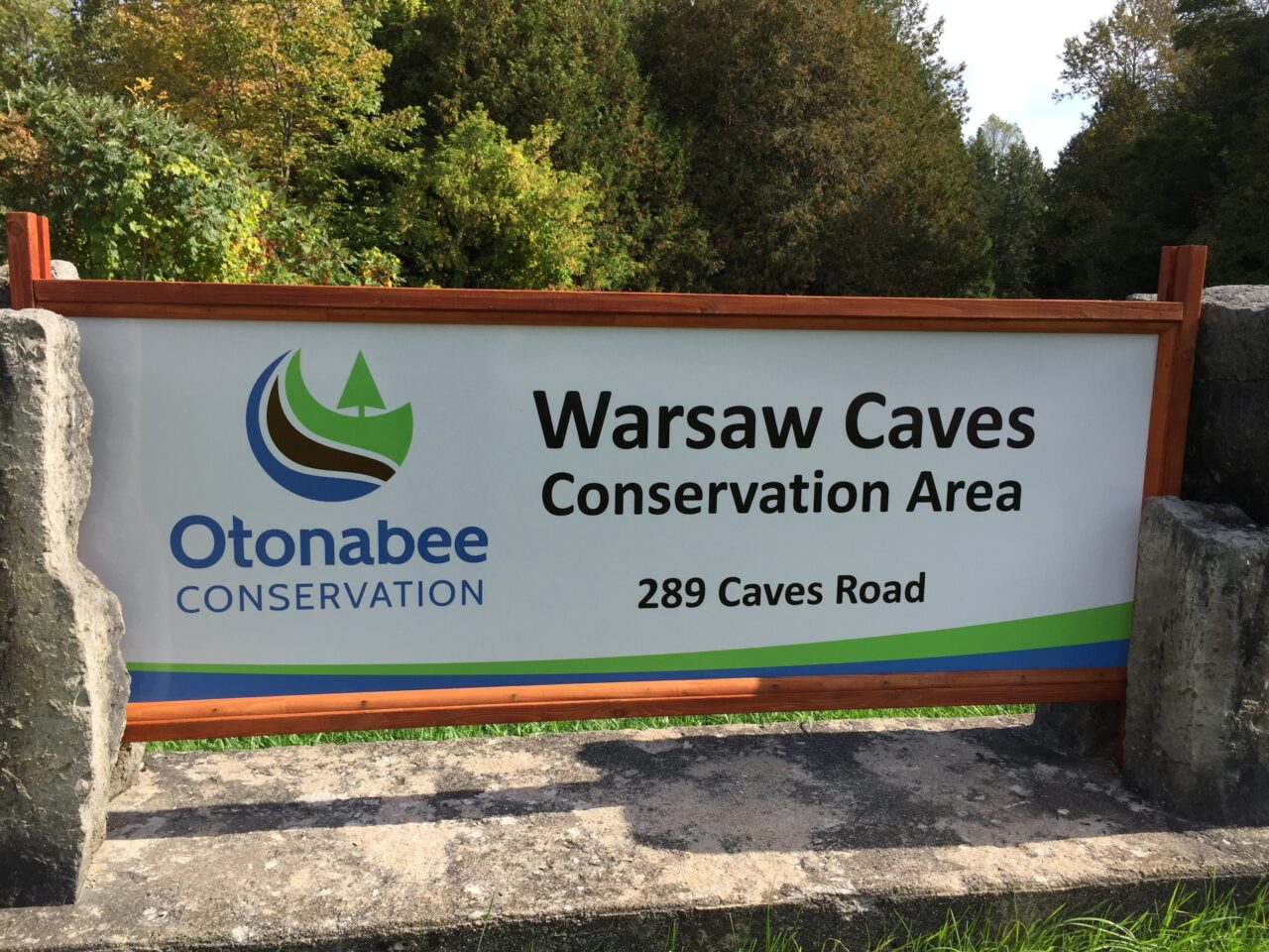 sign displaying warsaw caves conservation area with the otonabee conservation logo