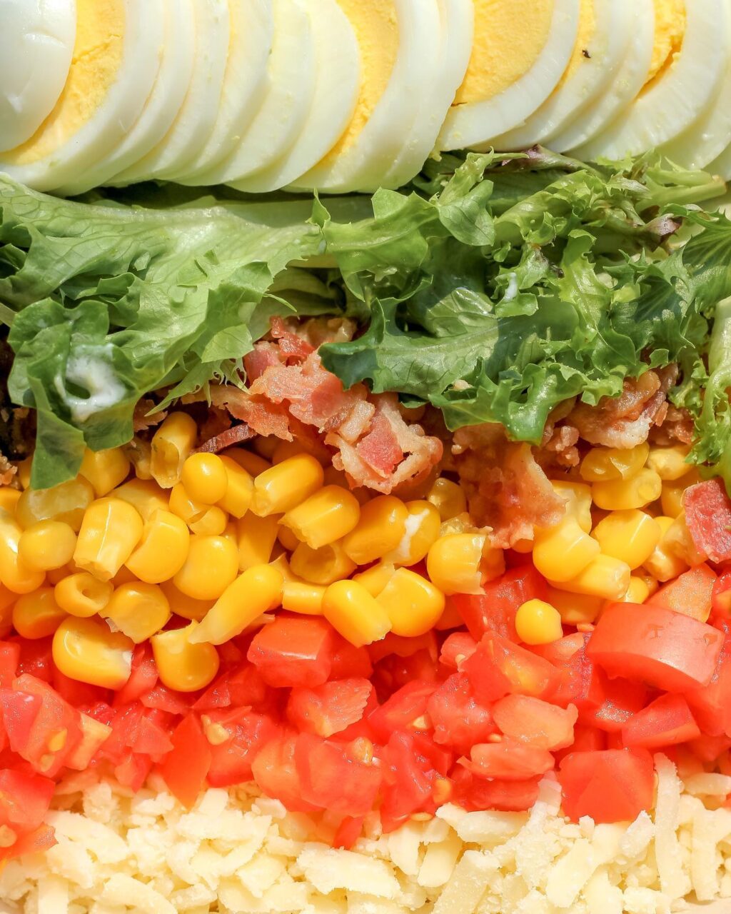Close up of salad, eggs, lettuce, bacon corn and tomatoes