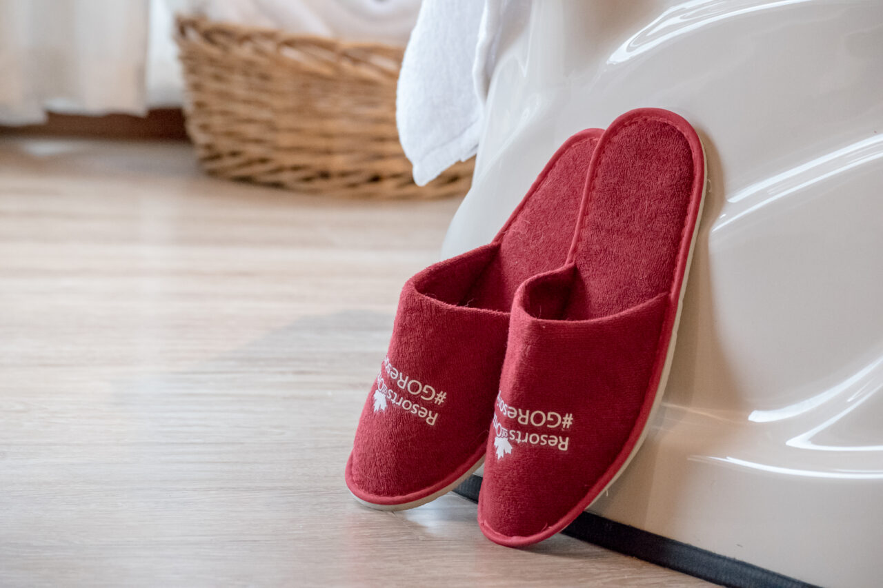 set of red slippers leaning against a bath