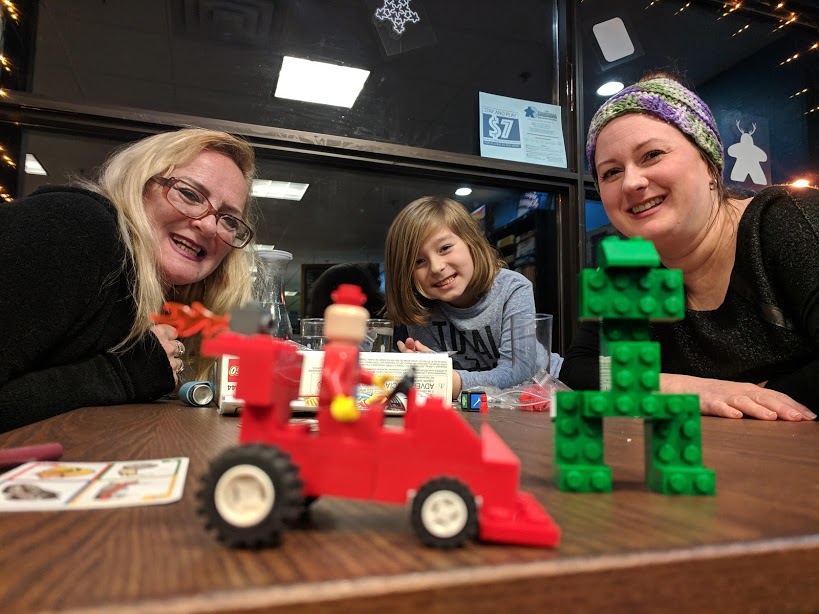 two adults and a child smiling next to lego toys