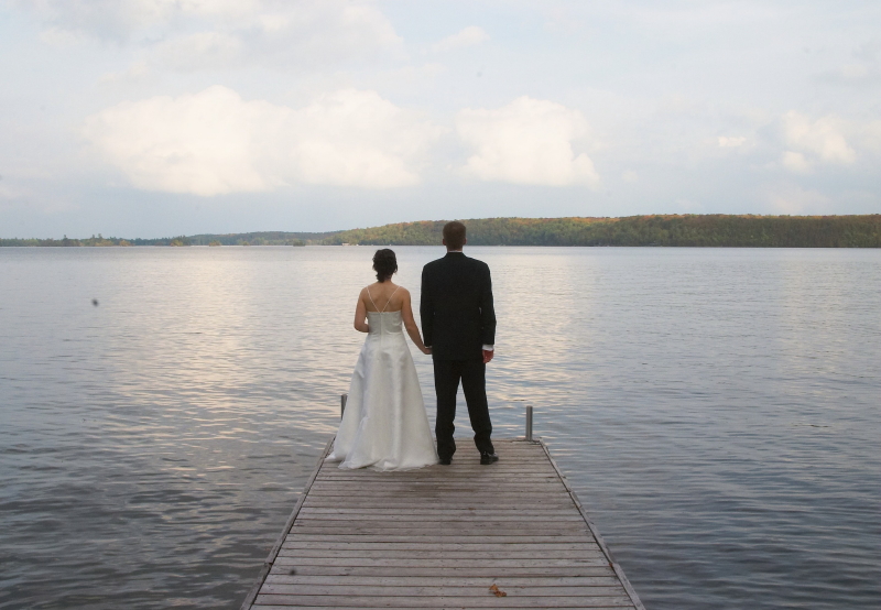 groom and bride on a dock facing water