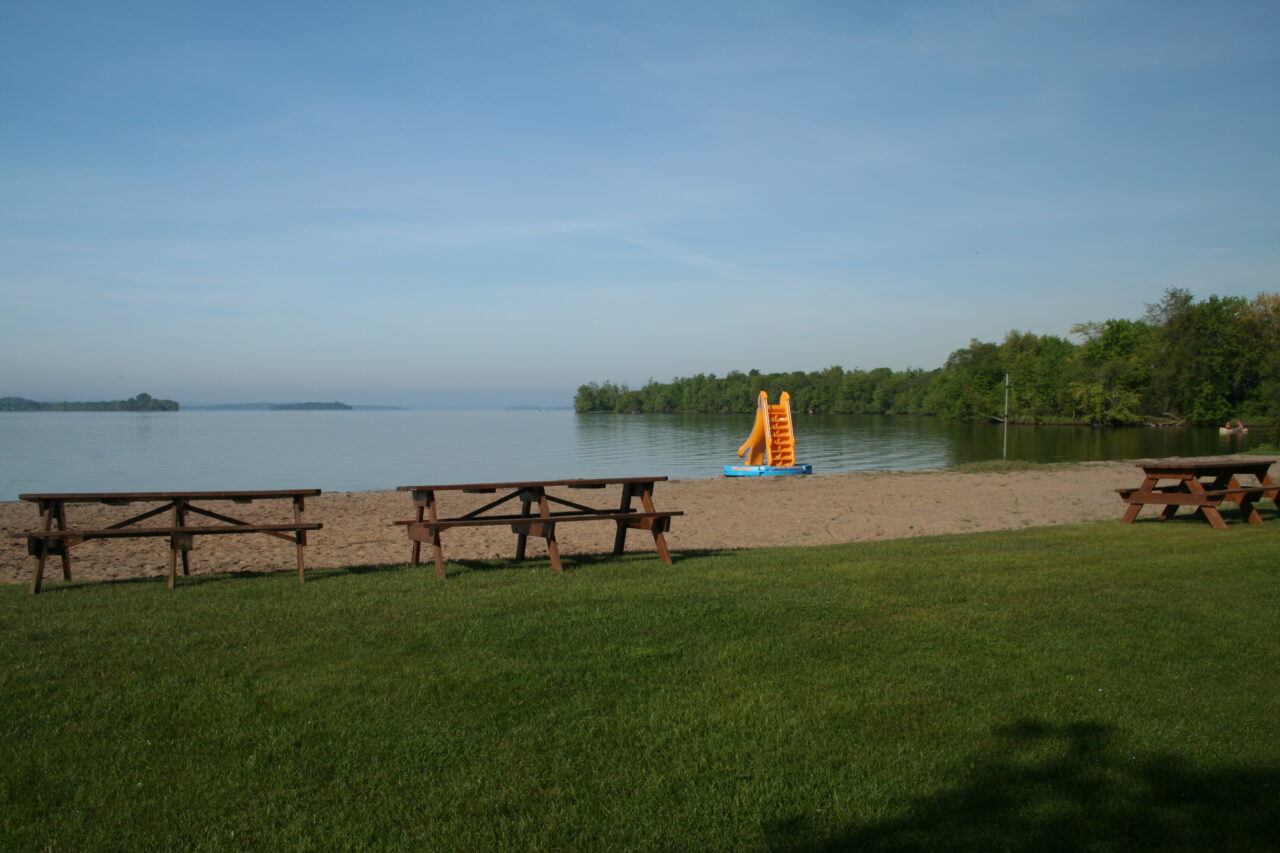 a lake beach with picnic tables