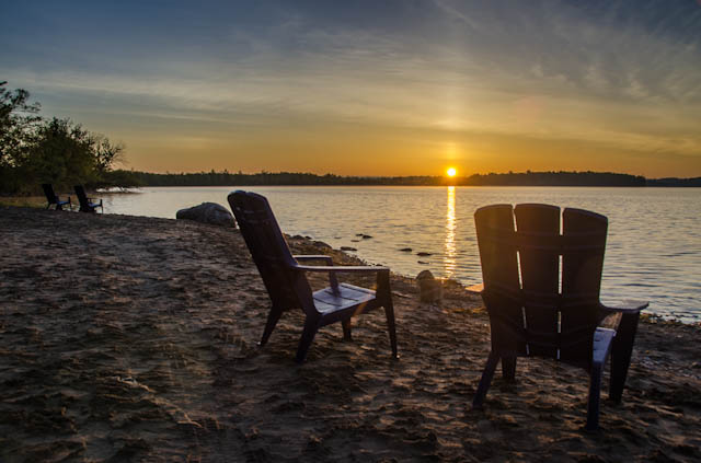 two chairs on a beach at sunset