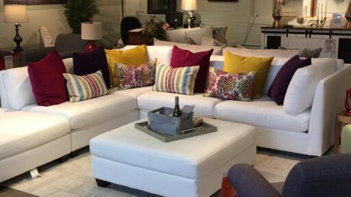 a white sectional and ottoman in a furniture showroom