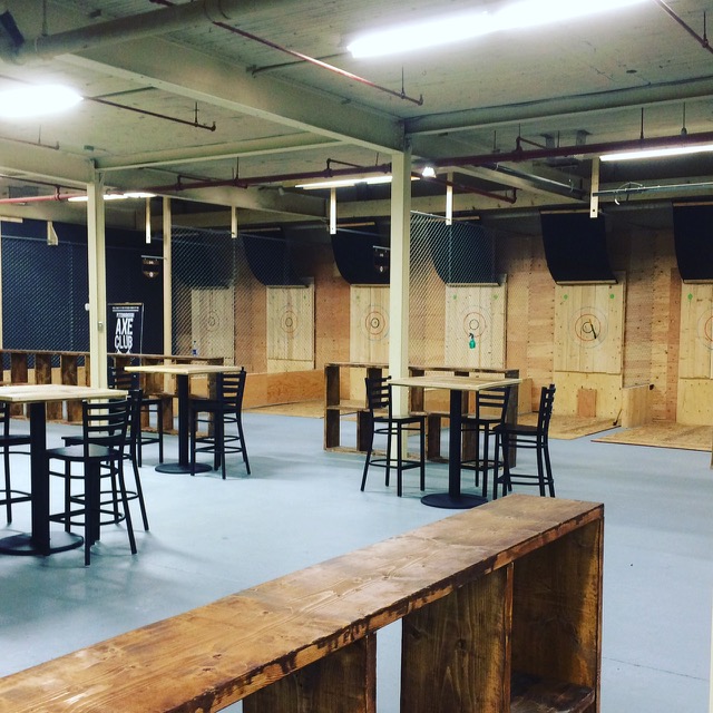 tables and chairs inside with axe throwing stations