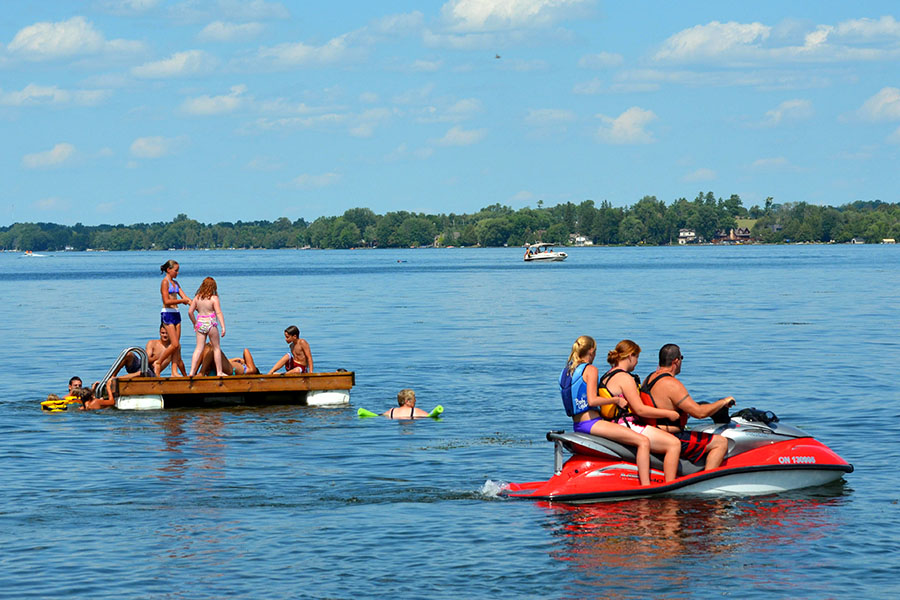 people riding a seadoo while others play on a floating dock