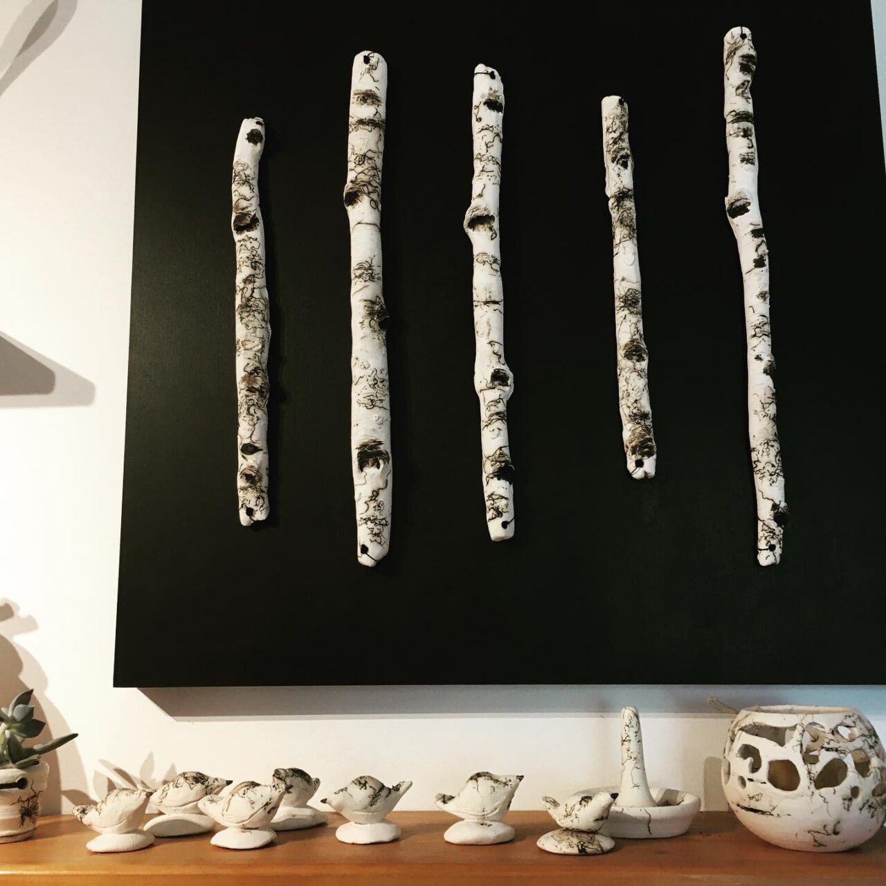 birch sticks on wall with pottery underneath