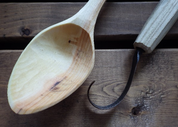 wooden carving spoon and hook knife on wooden table
