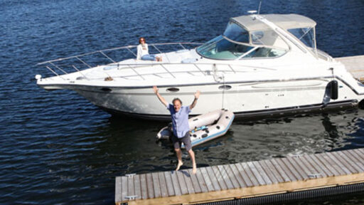 ma jumping on a dock. with a large boat in background