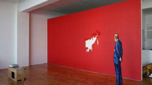 An oversized art piece featuring a red wall with an illustration of a man in front of it