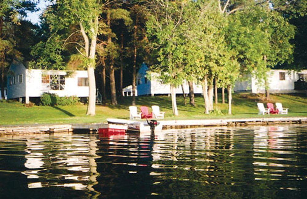 three cottages near the lake and a dock with three chairs
