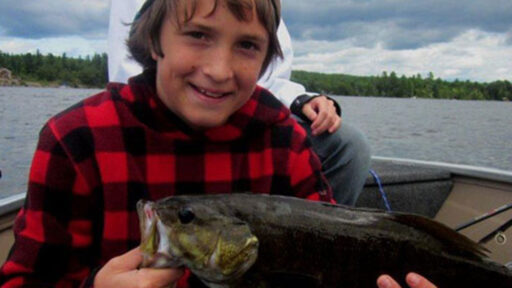 A kid happily holding a fish