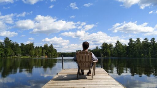 Man sitting in chair on dock looking at a lake