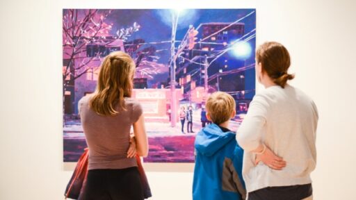A woman, man and child looking at a painting in a gallery