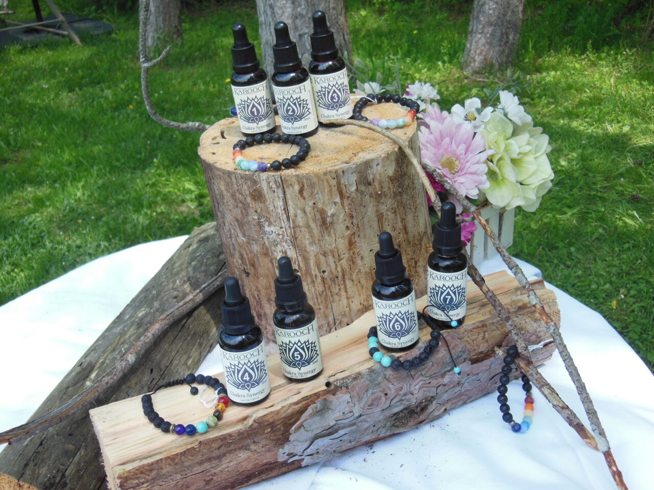 display of bracelets and bottles on rustic logs with flowers