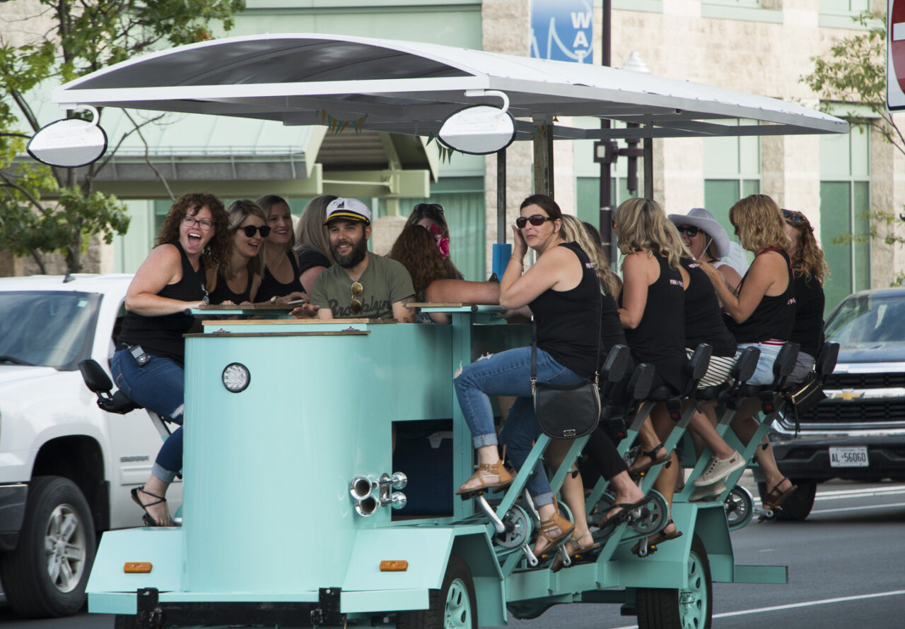 people pedaling on a street car bar
