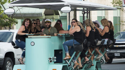 people pedaling on a street car bar