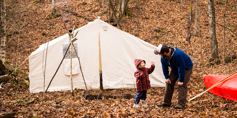 father & son talking in front of their camping tent