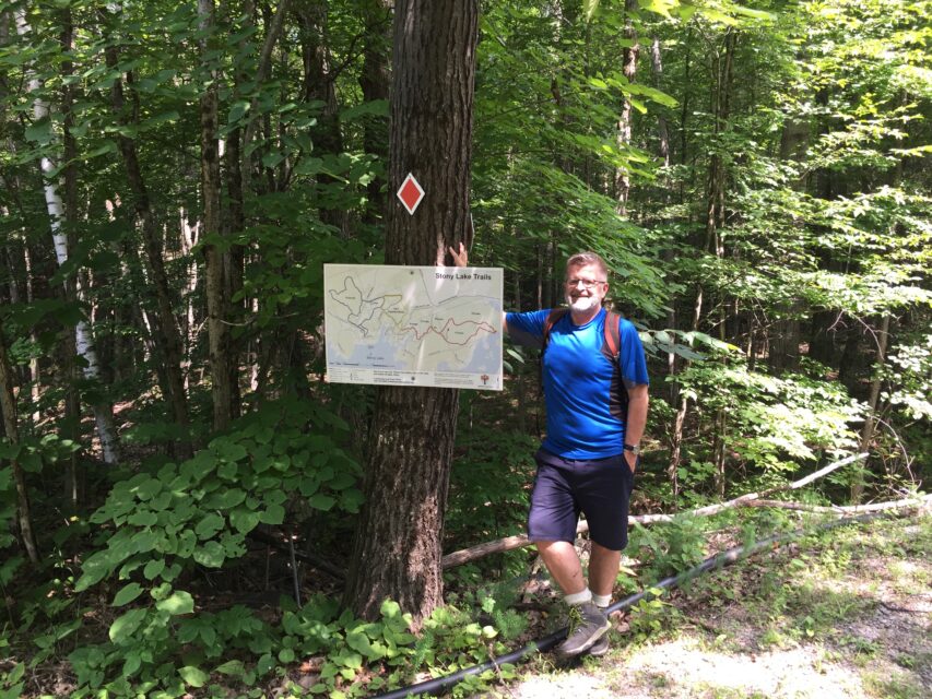 guy standing by trail sign in forest