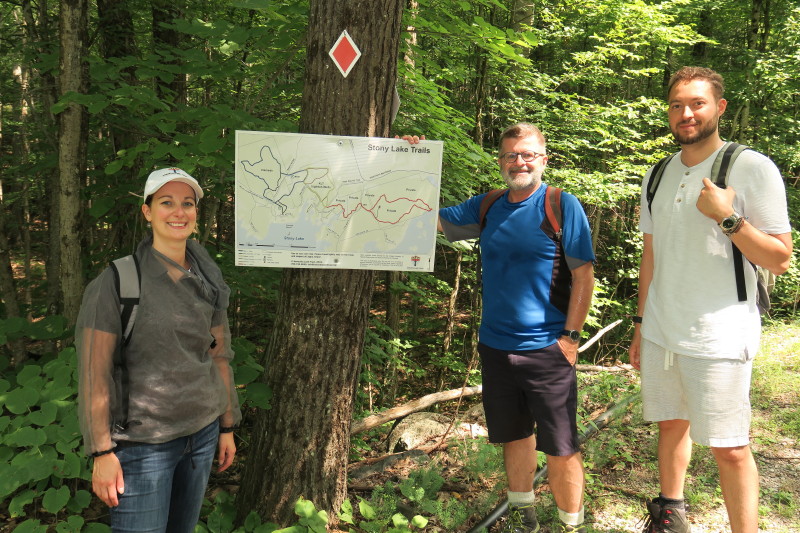 3 people standing by trail sign in woods