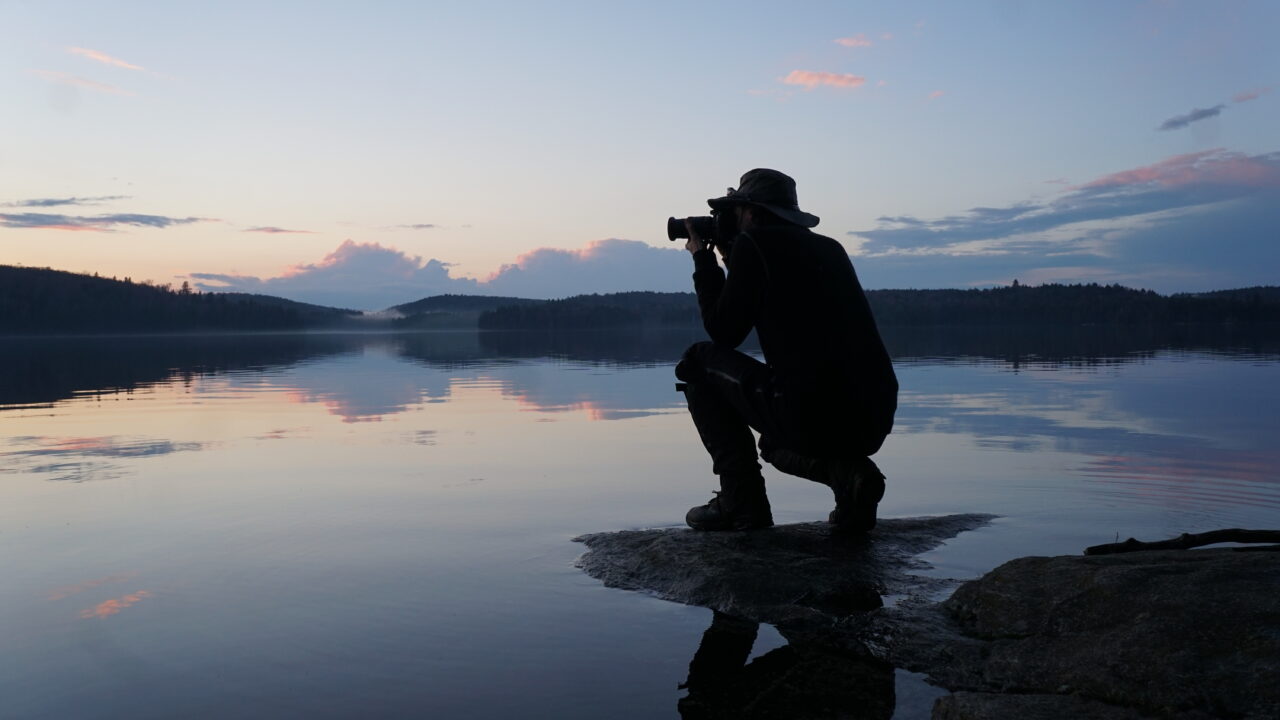 taking a picture of a lake in forest at sunrise
