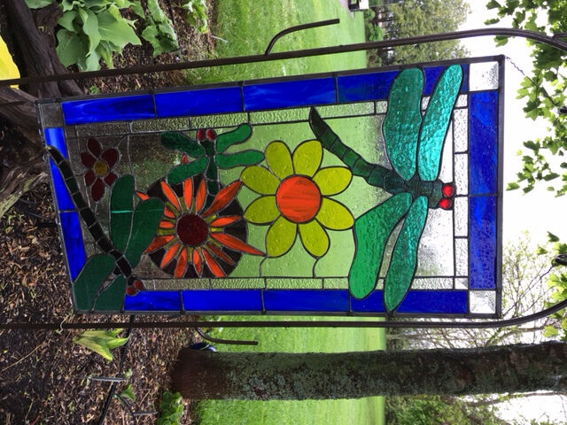 painted glass artwork of a dragonfly and flowers
