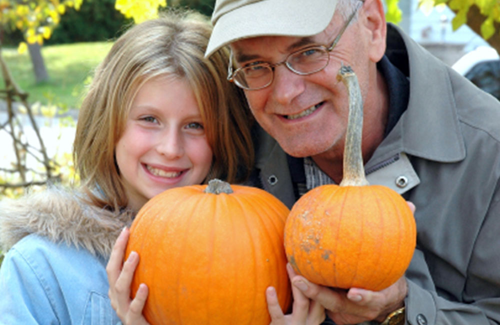 adult and child holding pumpkins and smiling