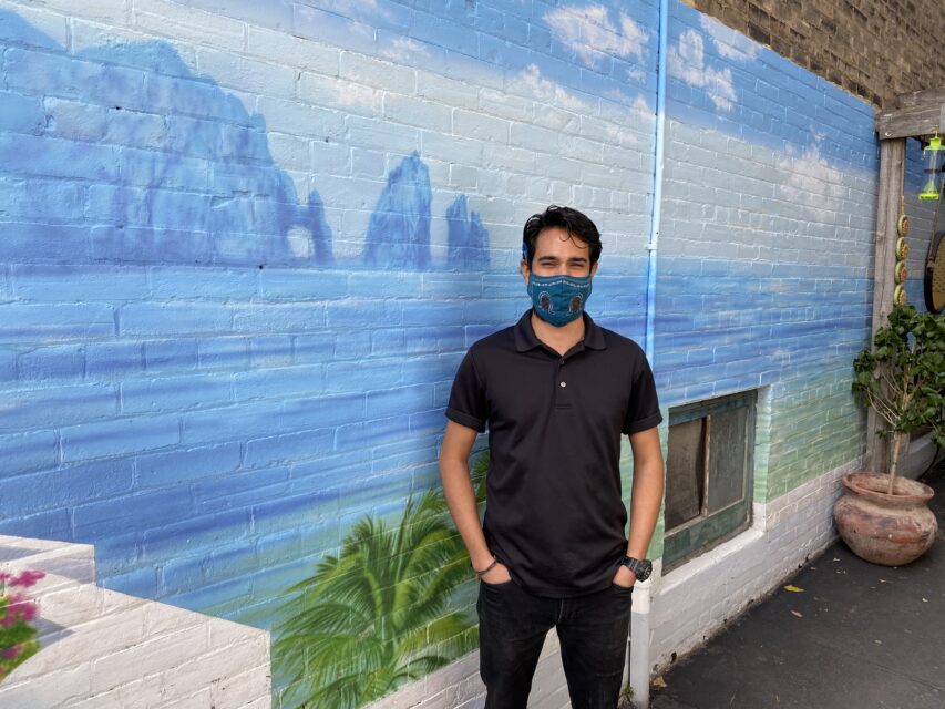 guy standing infront of a wall painted with a landscape