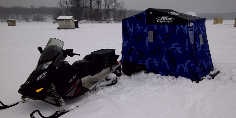 snow mobile and an ice fishing hut on lake