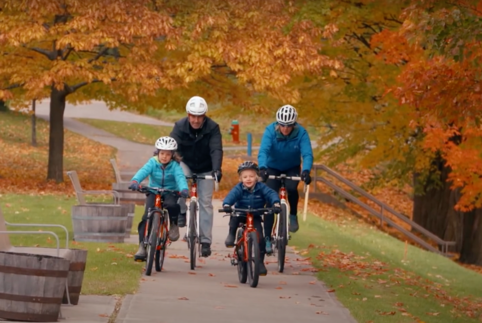 a family cycling down a sidewalk in the fall