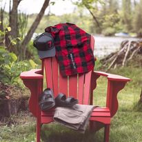 red plaid shirt, hat, sandals and shorts draped over a red lawn chair