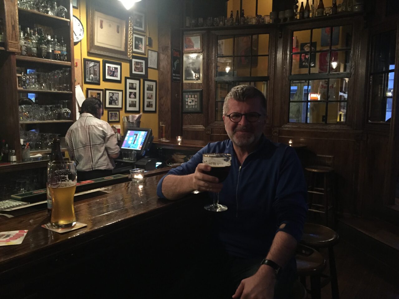 man sitting at a bar holding beer in a glass