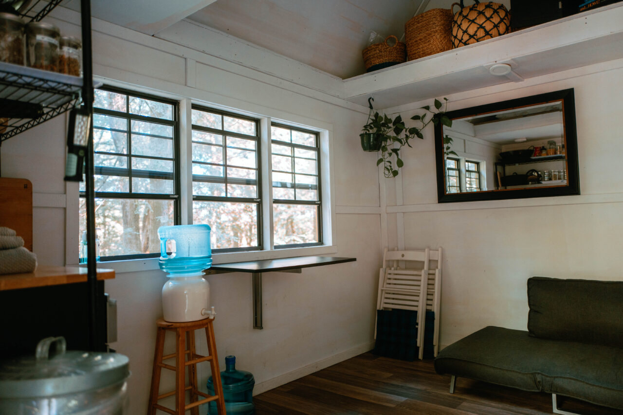 Inside of bunkie, white walls, black trim a stool in the corner with a blue water jug on it