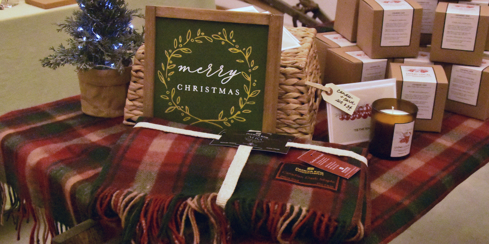 a table featuring a Merry Christmas sign, candles and a tartan blanket