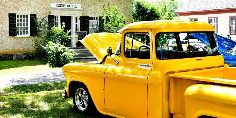 yellow vintage pickup truck with its hood open parked outside