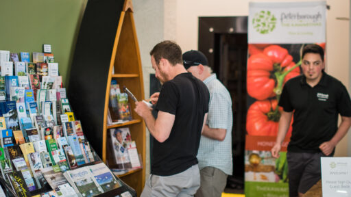 People looking at travel brochures on display at the Peterborough & the Kawarthas Visitor Centre