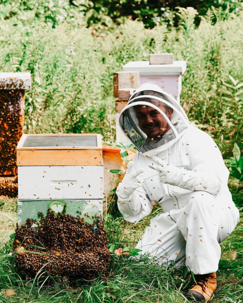 man in bee suit with hive