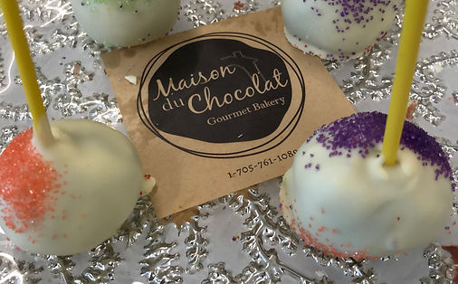 a Maison du Chocolat gourmet bakery business card with cake pops beside it