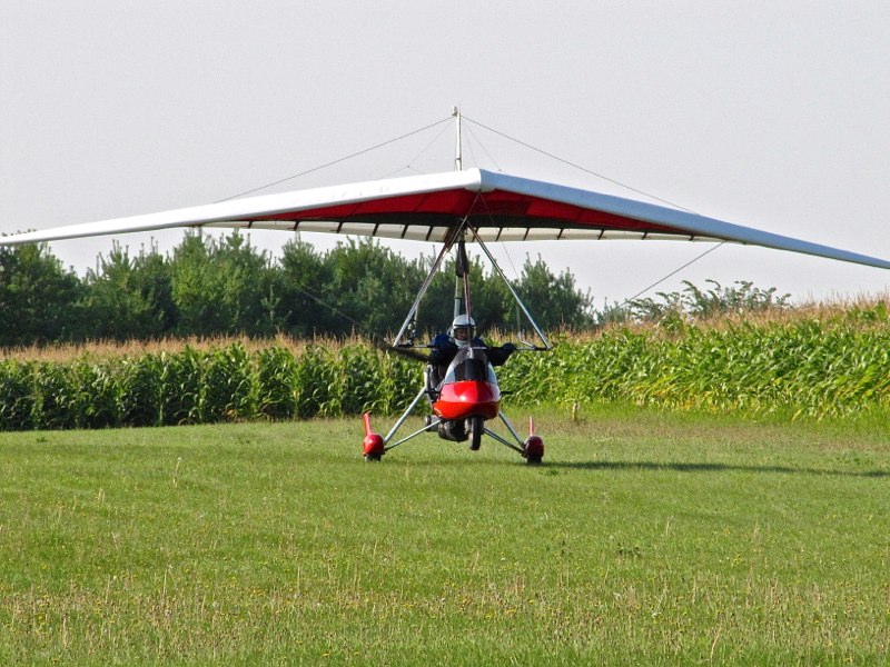 red aerotrike on grass with corn field behind