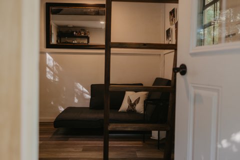 the living space of a tiny house with a couch and shelf