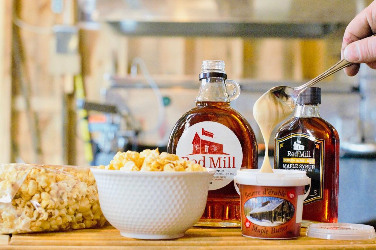 maple syrup, maple butter and popcorn displayed on a table