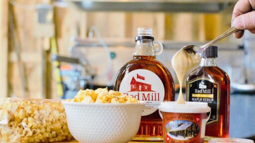 maple syrup, maple butter and popcorn displayed on a table