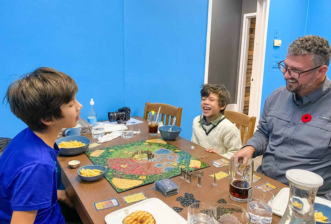 A man and two children eating and playing board games at a table