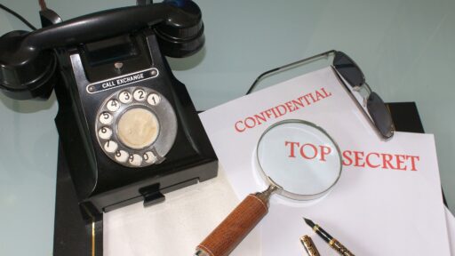 Table with a black rotary telephone, papers and a magnifying glass