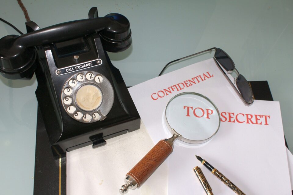 Table with a black rotary telephone, papers and a magnifying glass