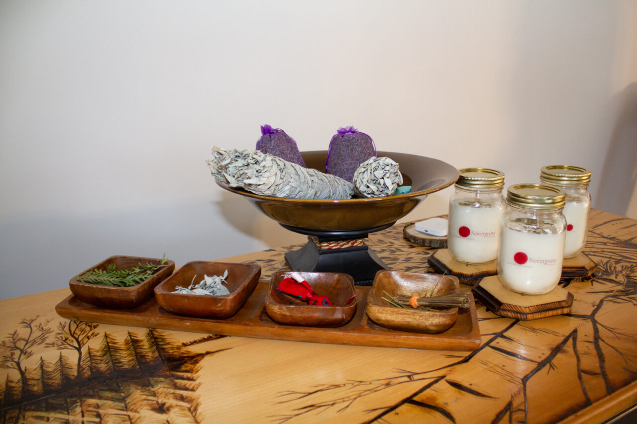 Table with candles and a bowl with sage and other natural products